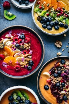 four bowls filled with different types of food on top of a blue tablecloth next to fruit and nuts