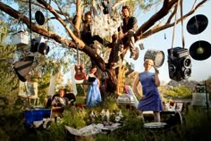 a group of people standing around a tree with records hanging from it's branches