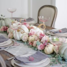 the table is set with white and pink flowers, silverware, and napkins