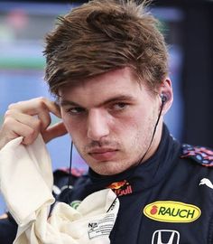 a close up of a person with ear buds in his ears and wearing a racing uniform