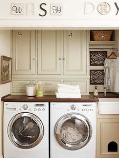 a washer and dryer in a small room with cabinets on the wall behind them