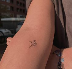 a woman's arm with a small flower tattoo on the left side of her arm