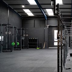 an empty gym with rows of squat racks and barbells on the floor in front of windows