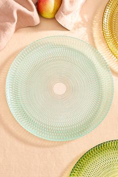 three glass plates sitting on top of a table next to an apple and napkins