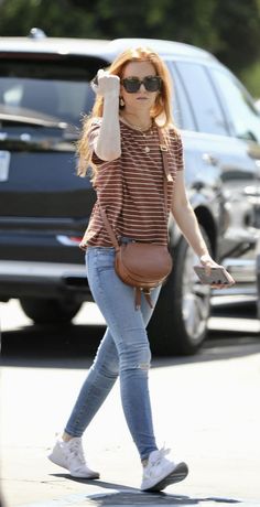 a woman walking down the street with her hand in her hair and wearing sunglasses on