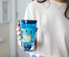 a woman holding a blue cup with a cartoon character on the side and a straw in her hand