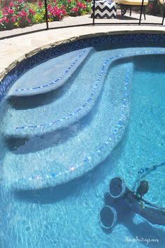 a man swimming in a pool with blue tiles on the side and steps leading up to it