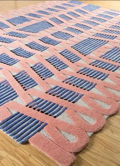 an area rug with blue and pink designs on it, sitting on a wooden floor