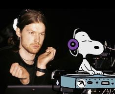 a man sitting in front of a record player with headphones on his ears and a cartoon dog behind him