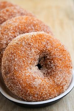 three sugar covered donuts in a white bowl