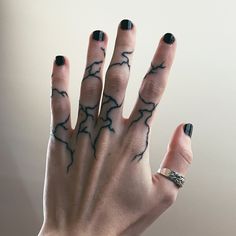 a woman's hand with black and white tattoos holding up her fingers to the camera