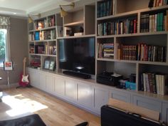 a living room filled with lots of bookshelves and a flat screen tv sitting on top of a wooden floor