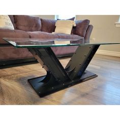 a glass table sitting on top of a hard wood floor next to a brown couch