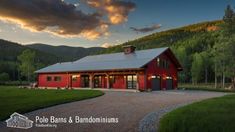 a red barn sits in the middle of a grassy field with mountains in the background