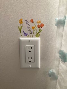 an electrical outlet with flowers painted on it