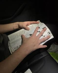 a person sitting in a car with their hand on an open book that is being held by someone