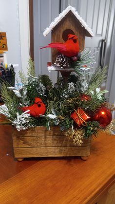 a wooden box filled with christmas decorations on top of a table next to a birdhouse