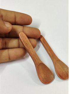 two wooden spoons in the palm of someone's hand