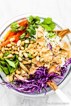 a glass bowl filled with different types of vegetables and sauces on top of it