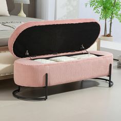 a pink ottoman with two candles in it on a white floor next to a bed