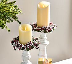 two white candles are sitting on a table