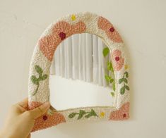 a person holding up a mirror with flowers on it