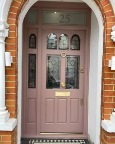 a pink front door with glass panels and number 25 on the side entrance to a brick building