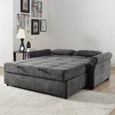 a grey couch sitting on top of a white rug