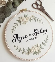 a white embroidered wedding ornament with flowers and greenery next to some scissors