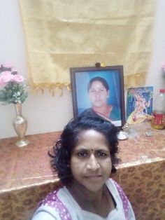 a woman sitting in front of a portrait on a table