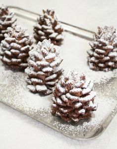 small pine cones covered in powdered sugar on a glass tray with silver spoons