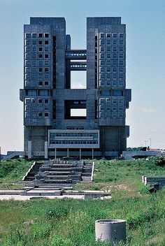 a very tall building sitting on top of a lush green field