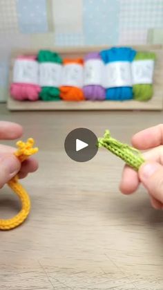 two hands holding small crochet items on a table