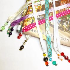 several lanyards with different colored beads hanging from them on a white table next to a book