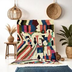 a multicolored area rug on the floor next to a plant and potted plants