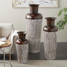 three brown vases sitting next to each other on a table in front of a couch