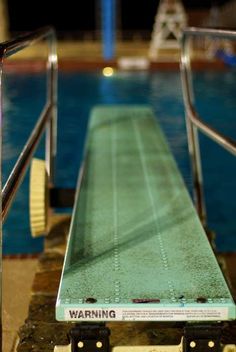 a long wooden bench sitting next to a swimming pool with steps leading up to it