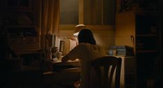 a woman sitting at a desk in the dark