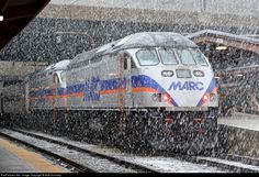 a train is coming down the tracks in the snow with it's lights on