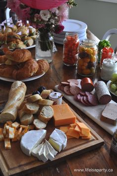 a wooden table topped with lots of different types of cheeses and meats on top of it