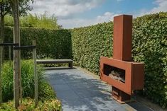 an outdoor fire place surrounded by hedges and trees