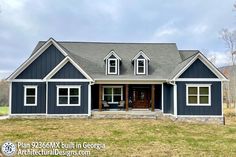 a blue house sitting in the middle of a grass covered field with lots of windows