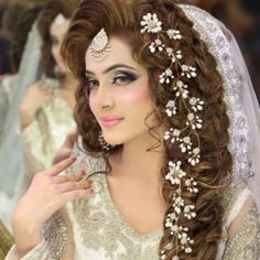 a woman with long hair wearing a bridal gown and jewelry on her head is posing for the camera