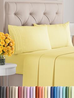 a bed with yellow sheets and flowers in a vase