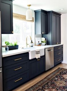 a kitchen with dark blue cabinets and white counter tops, an area rug in front of the sink