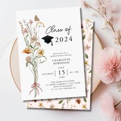 a graduation party card with flowers on it and a pink flower arrangement next to it