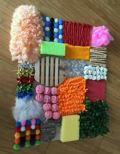 several different types of items are laid out on a wooden floor, including yarns and pom poms