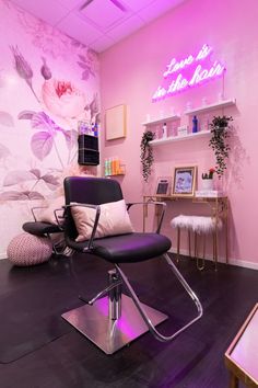 the salon is decorated with pink flowers and purple lighting, along with black leather chairs