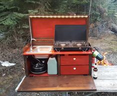 an outdoor cooking area with a stove, sink and coffee pot on the table next to it