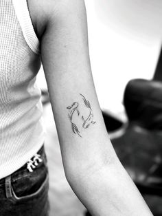 a black and white photo of a woman's arm with a koi fish tattoo on it